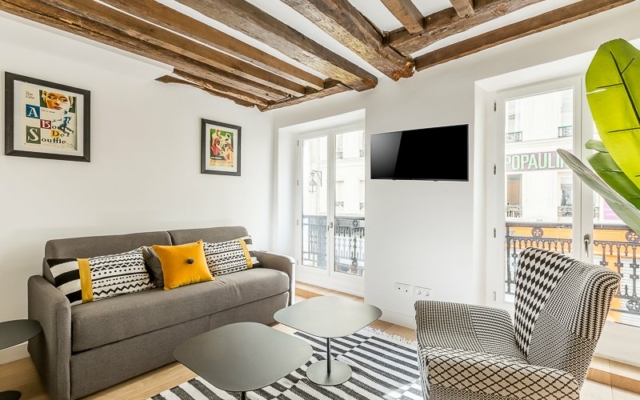 Montorgueil Salon avec canapé, fauteuil, table basse et TV.