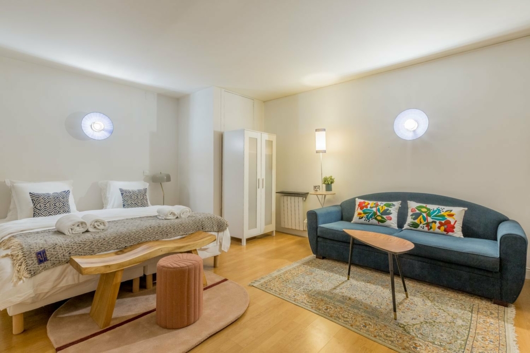 Suite avec grand lit double, canapé bleu et penderie.