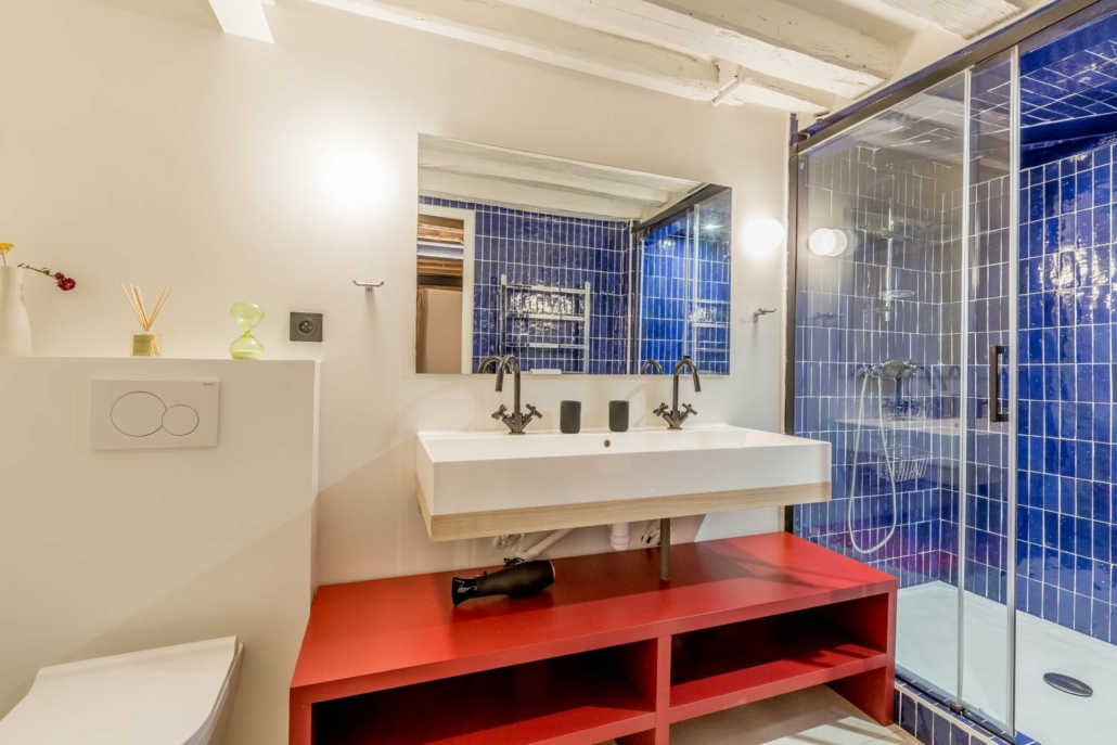 Salle de bain spacieuse avec double évier et grande cabine de douche.