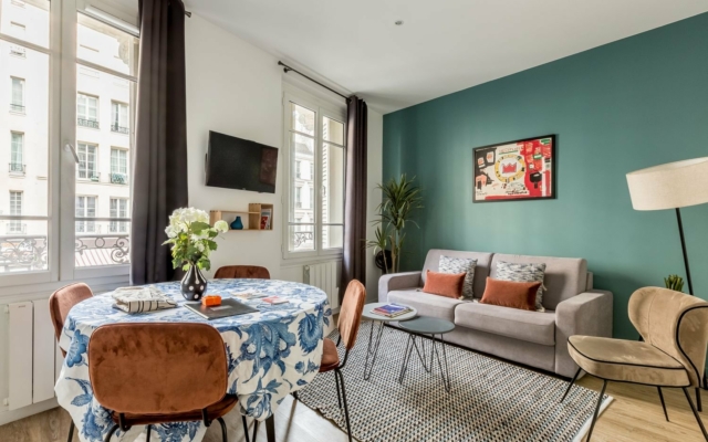 Réaumur Salon avec mur vert et équipé d'un canapé, fauteuil et TV.