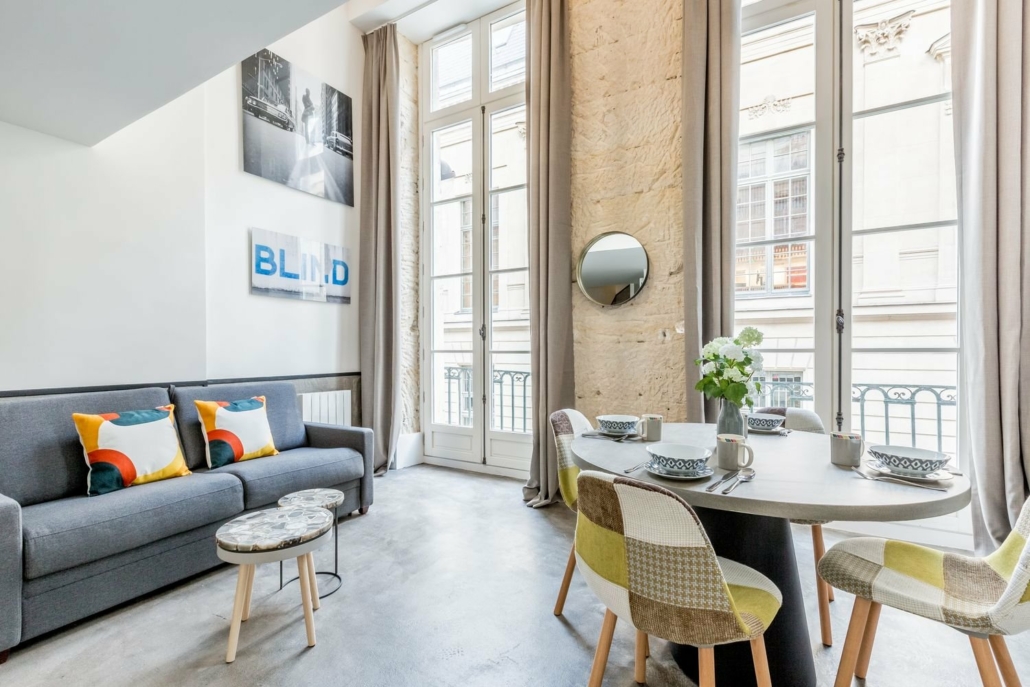 Salle à manger avec table et canapé, portes fenêtres.