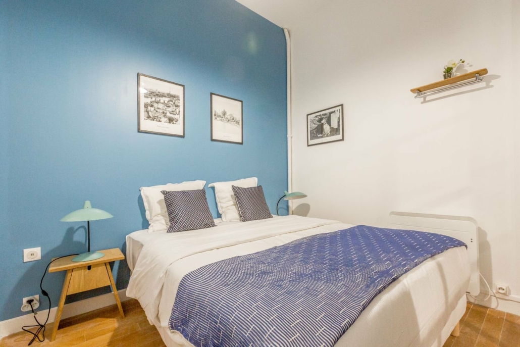 Chambre avec lit double, spacieuse et décoration tons bleus.
