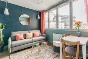 suites urbaines Porte de Versailles, salon turquoise avec canapé et déco tons chauds / beiges.