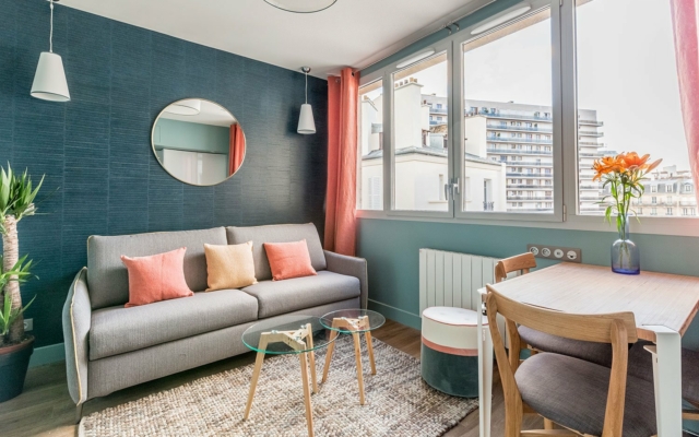 suites urbaines Porte de Versailles, salon turquoise avec canapé et déco tons chauds / beiges.