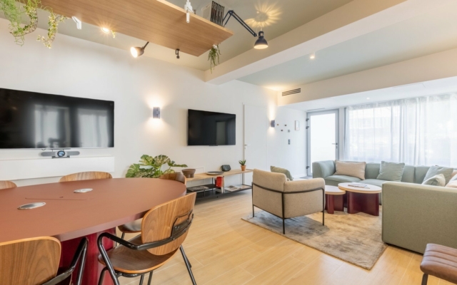 Suite urbaine avec grand salon, canapé et fauteuils, équipée d'une TV.