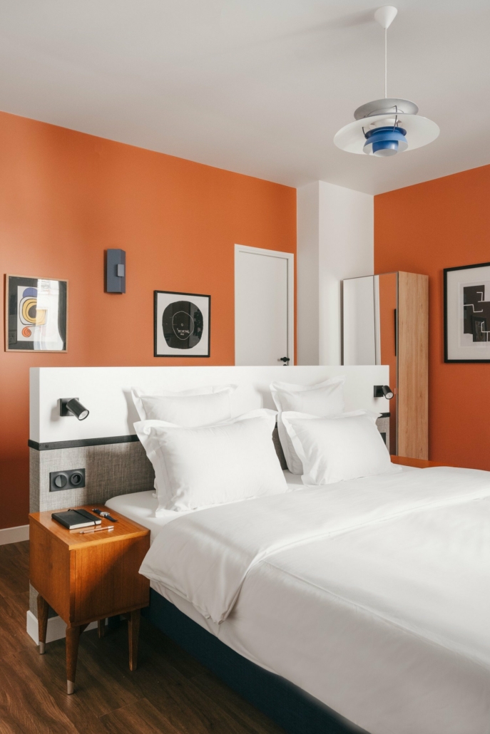 Grande chambre avec lit double, décoration moderne dans les tons oranges.