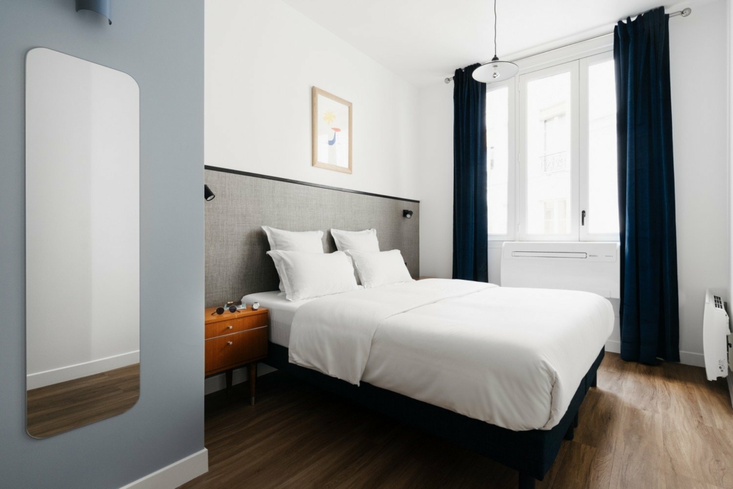 Chambre avec lit double, spacieuse et décoration bleu-gris.