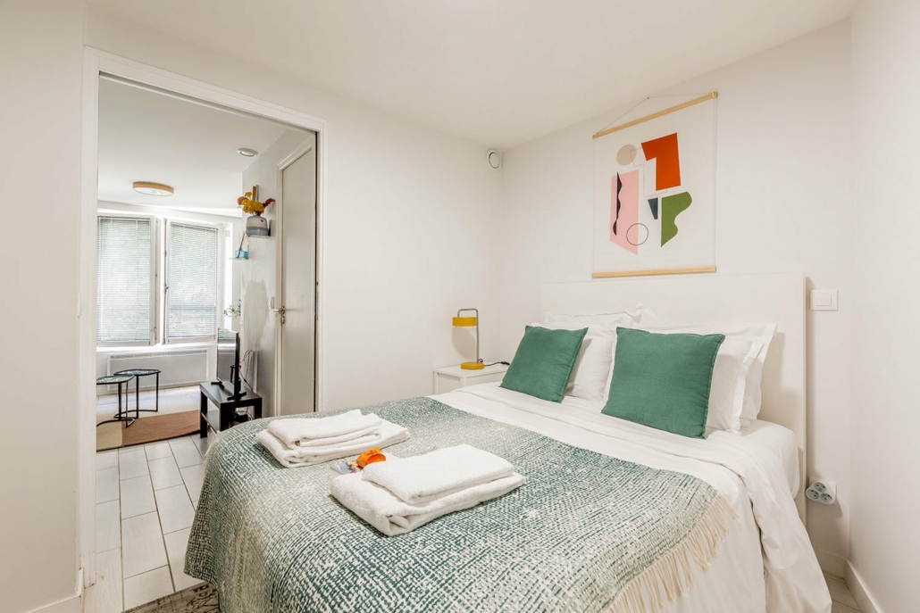 Chambre avec lit double, décoration tons blanc et vert.