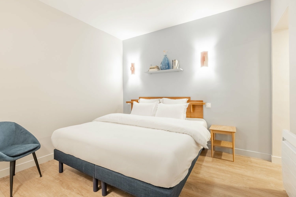 Chambre avec lit double, décor épuré et dans des tons pastels.