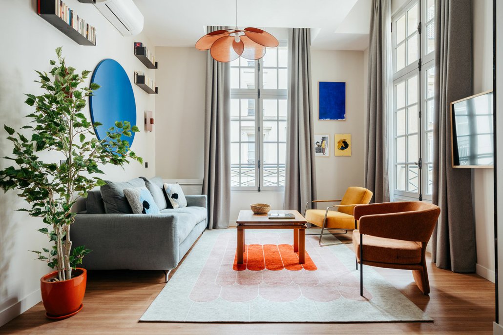 Suite urbaine dans le quartier du Louvre. Salon avec canapé, fauteuil et TV. suites urbaines décorées dans des tons chauds.