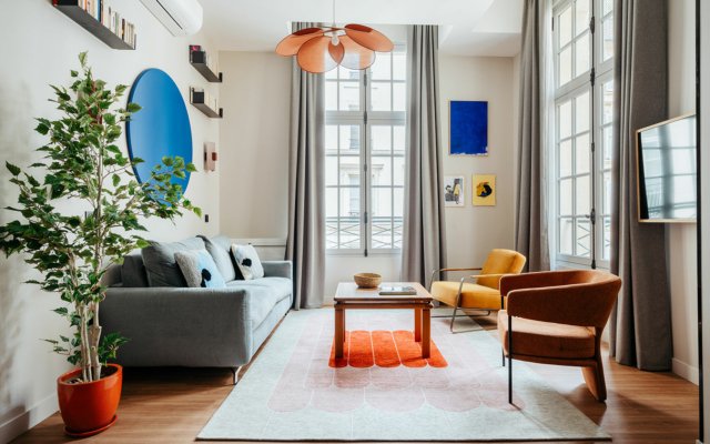 Suite urbaine dans le quartier du Louvre. Salon avec canapé, fauteuil et TV. suites urbaines décorées dans des tons chauds.
