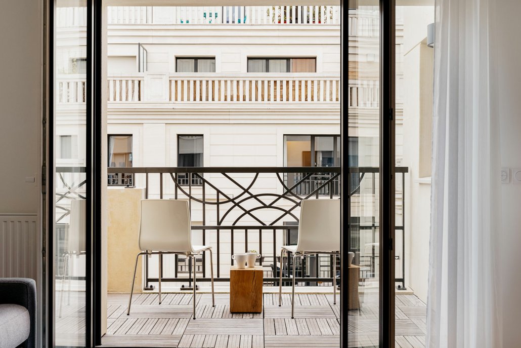 Balcon avec chaises et table basse, vue sur rue.