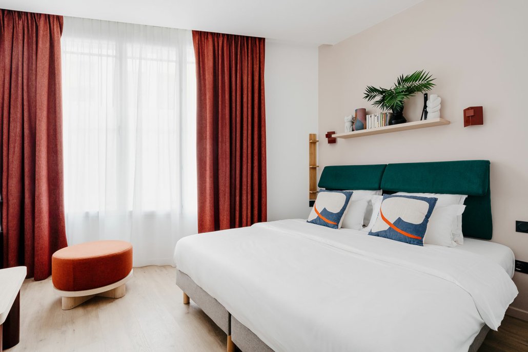 Chambre lit double, décoration épurée et tons chauds.